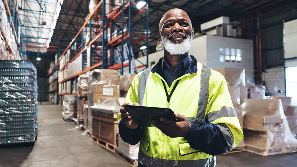 smiling warehouse worker with tablet